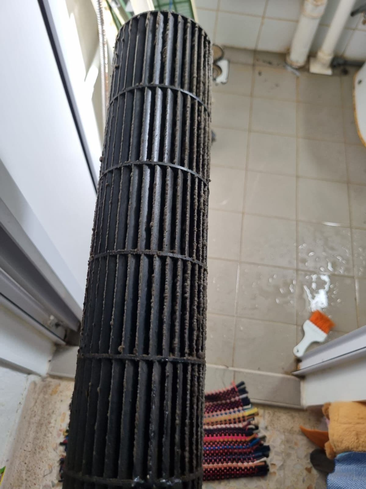 A dirty aircon blower fan being cleaned during servicing