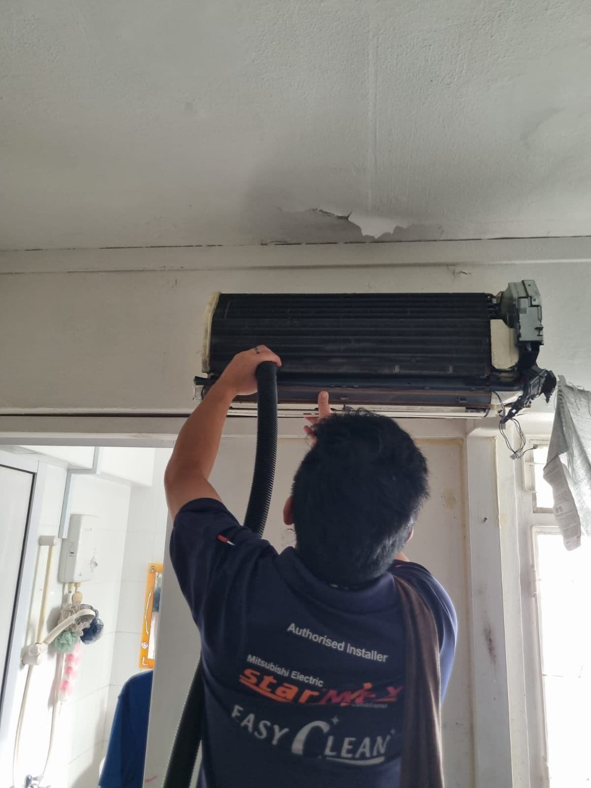 Technician vacuuming dust from an aircon evaporator (cooling) coil