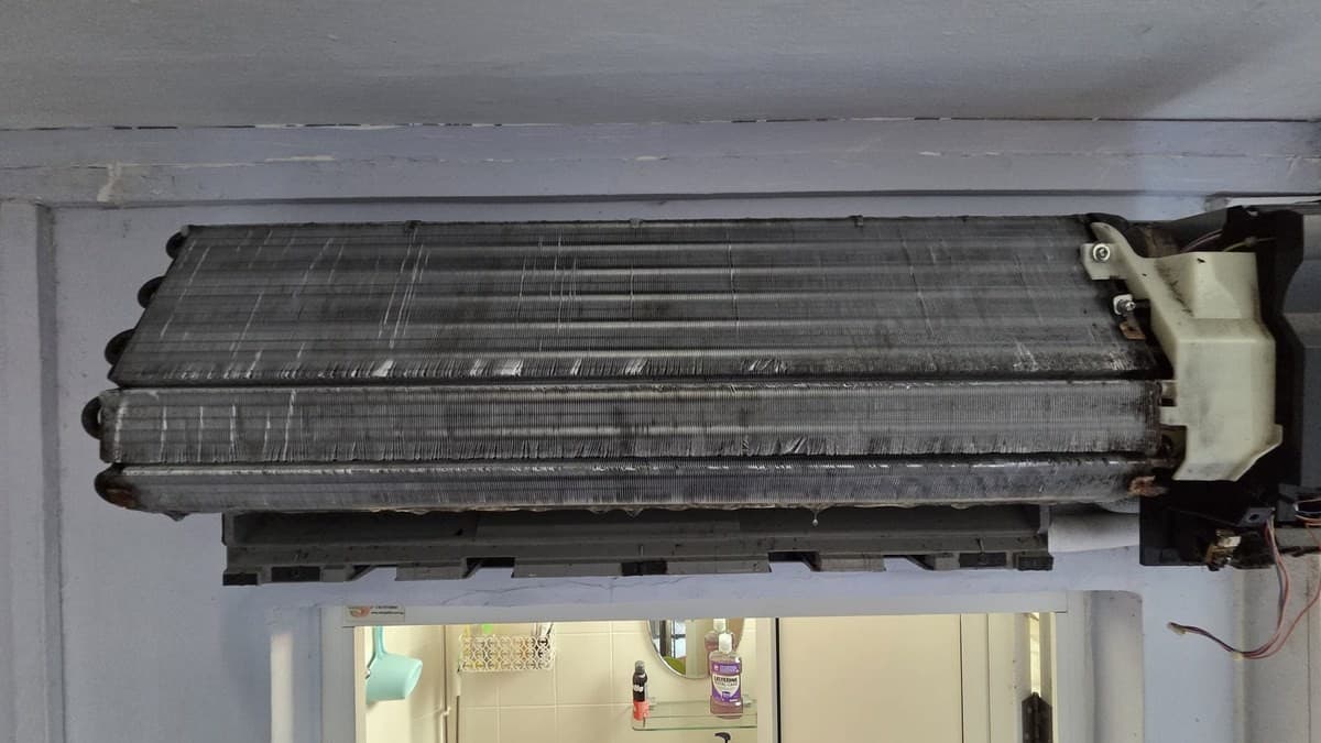 Wall-mounted aircon with the cover off, cooling coil completely black with built-up dust and grime