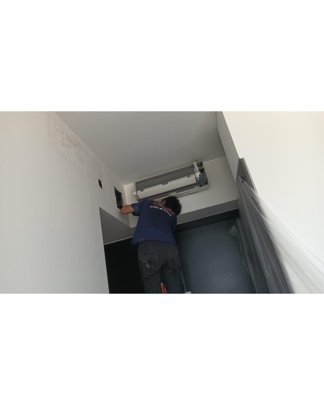 Technician working at the wall beside the aircon unit where the old mounting position left marks to be patched
