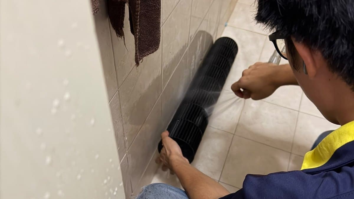 Technician washing a dirty aircon blower wheel with water